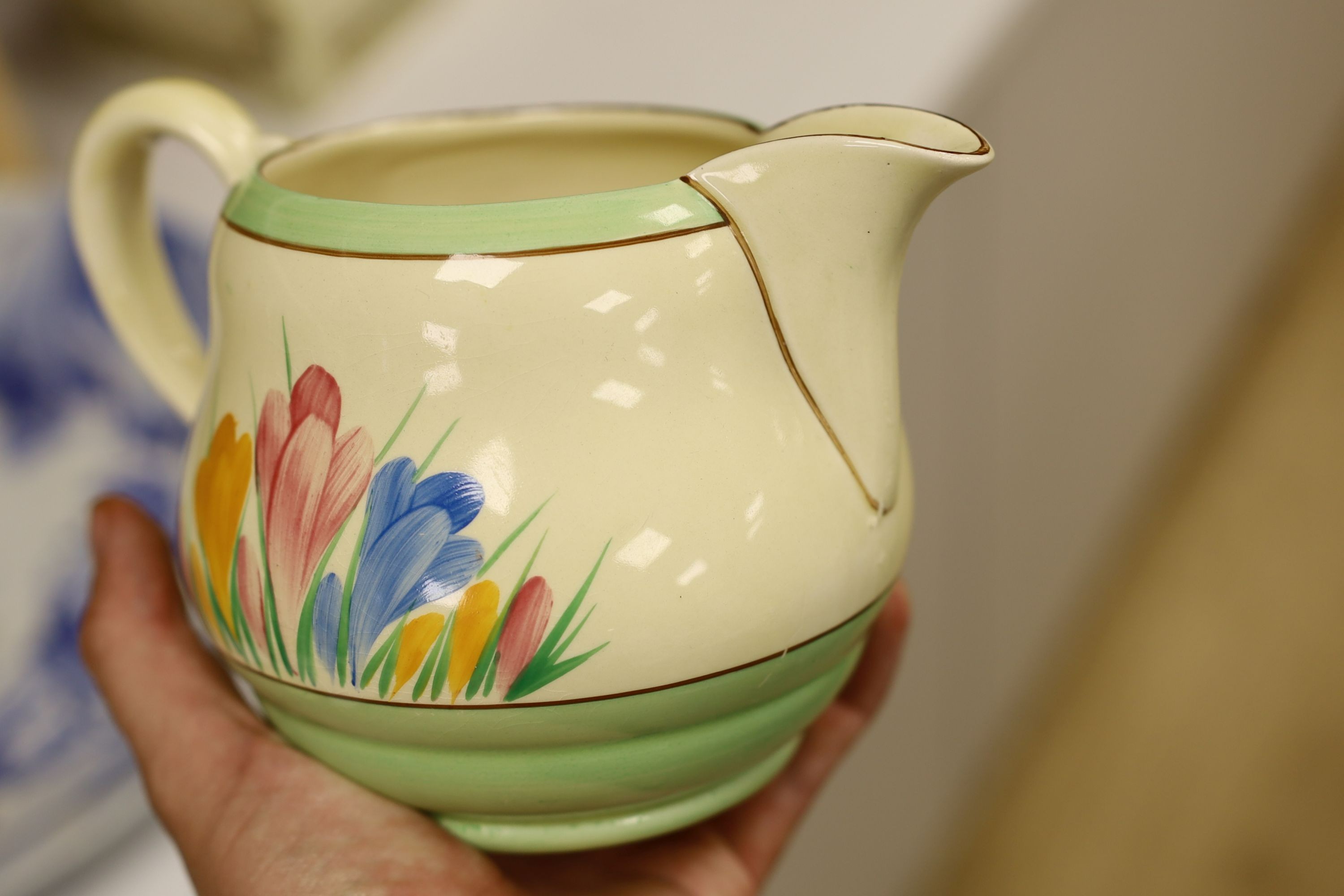 A Clarice Cliff crocus design milk jug and a Bizarre patterned side plate, jug 11.5 cms high